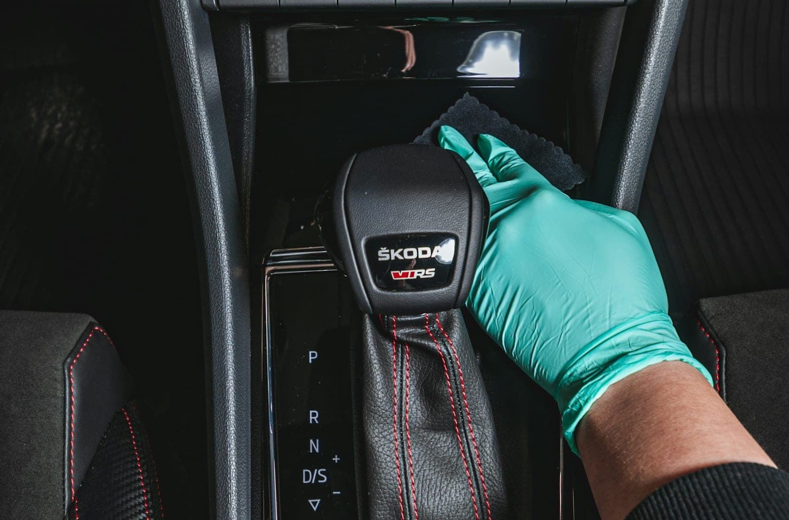 A detailer in gloves wiping down a car's center console